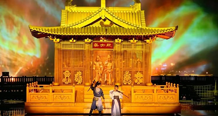 Espectáculo en vivo en el escenario con dos artistas en trajes de época frente a un telón de fondo de templo dorado y luces vibrantes.