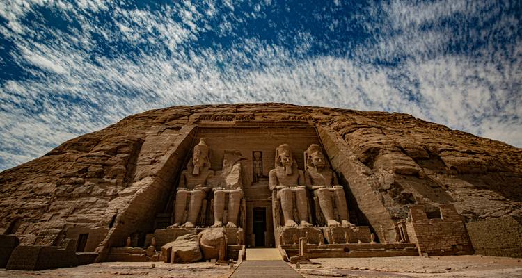 Vue large en contre-plongée du temple d'Abou Simbel contre un ciel texturé dramatique.