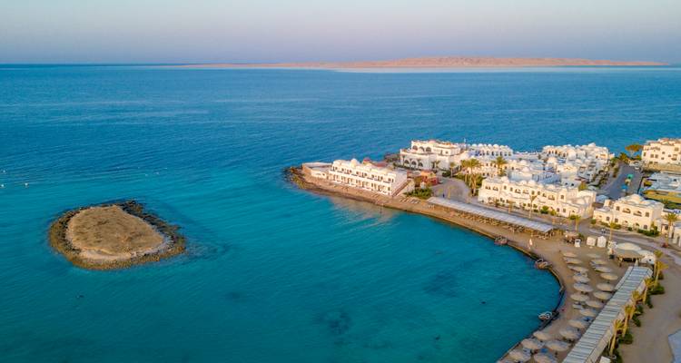 Vue aérienne de la mer Rouge turquoise entourant une presqu'île de villégiature blanche avec un petit îlot à proximité