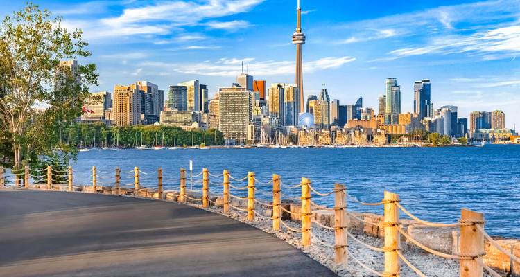 Skyline von Toronto mit dem CN Tower, der sich über moderne Gebäude erhebt, von jenseits des Lake Ontario an einem sonnigen Nachmittag betrachtet