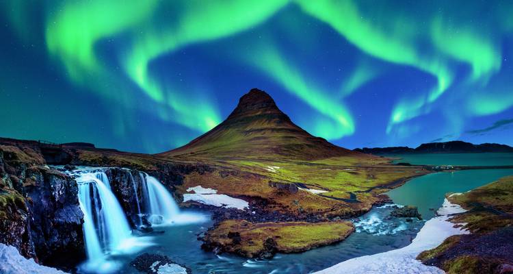 Noorderlichten die heldere groene bogen vormen boven de sneeuwbestoven berg Kirkjufell en watervallen 's nachts.