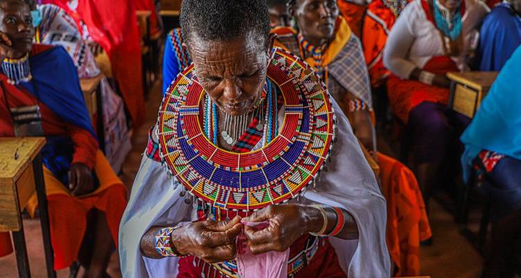 Femme Maasai réalisant un travail de perles coloré à l'intérieur d'une salle de classe communautaire