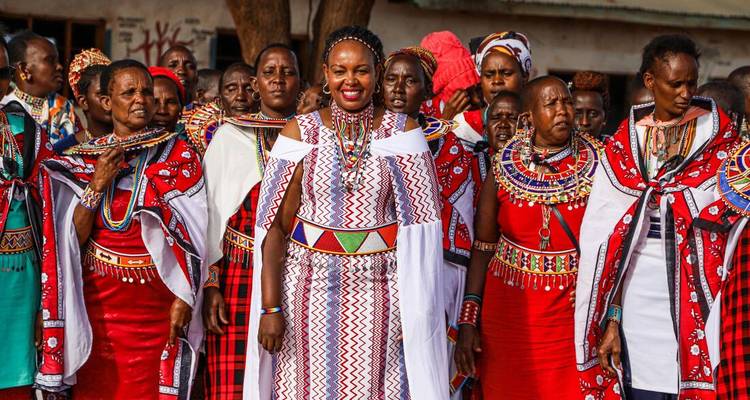 Grand groupe d'hommes et de femmes Maasai vêtus de tenues traditionnelles aux couleurs vives posant en extérieur