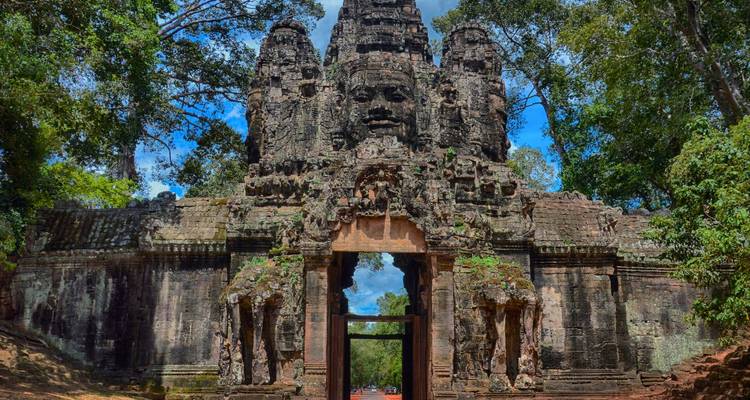 Puerta de piedra monumental con rostros serenos a la entrada de Angkor Thom enmarcada por la selva.