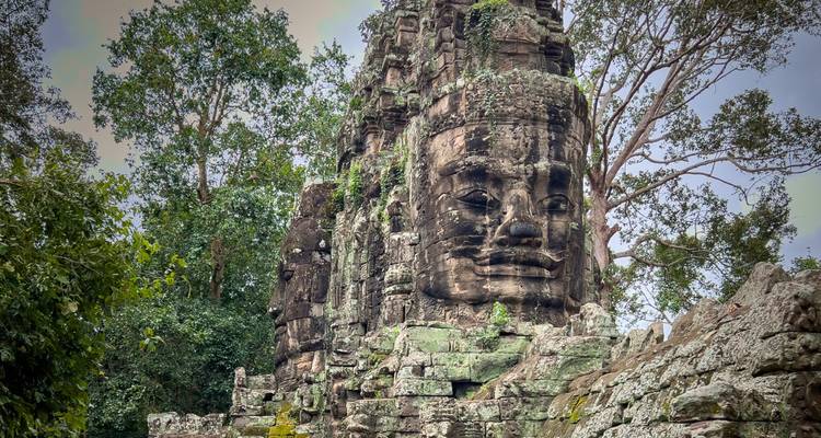 Primer plano de una gigantesca torre con cara de piedra desgastada por el tiempo en el complejo de Angkor de Camboya.