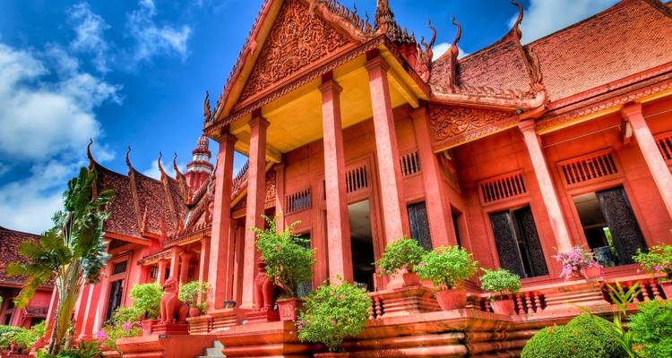 El Museo Nacional de Camboya, con sus tonos rojizos, destaca contra un cielo azul brillante y unos jardines exuberantes.