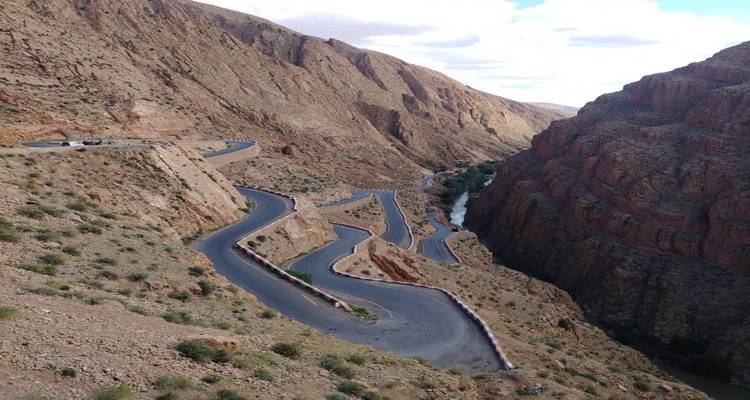 Route emblématique sinueuse creusée dans les parois abruptes des Gorges du Dadès avec une rivière loin en dessous