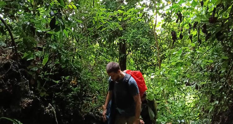 El trekker líder sube entre la selva enmarañada mientras un guía lo sigue atrás entre la vegetación.