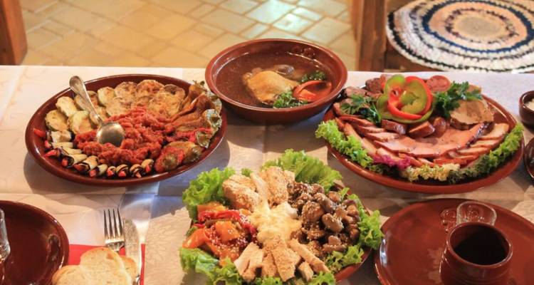 Tafel uitgespreid met assortiment traditionele Moldavische gerechten waaronder vlees, salades en soepen.