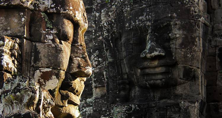 Moss-covered stone faces of Bayon temple bathed in soft light