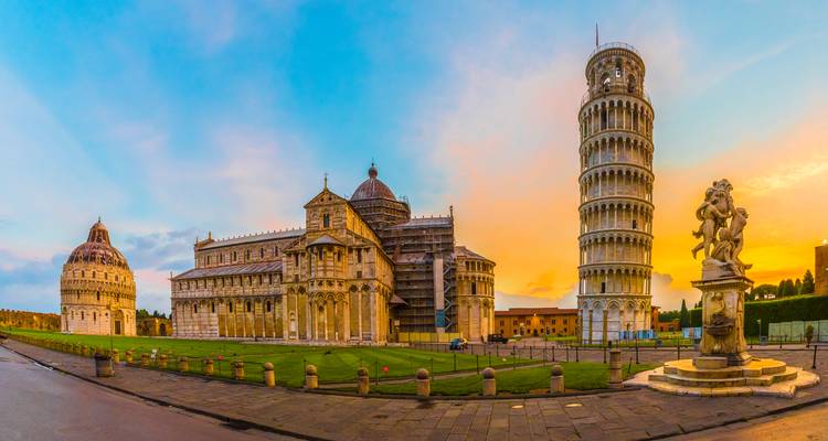 Sonnenuntergang-Panorama von Pisas Piazza dei Miracoli mit dem Baptisterium, dem Dom, dem Schiefen Turm und einer Statue.
