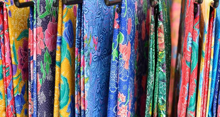 Des rangées de tissus aux motifs colorés et éclatants suspendus à l'affichage dans un étal de marché.
