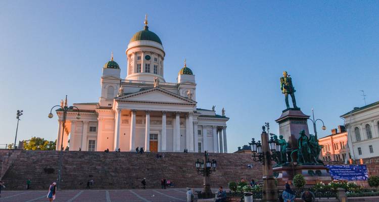 Senate Square in Helsinki with the cathedral basking in golden hour light and people scattered on the wide steps.