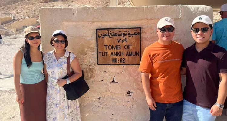 Les voyageurs posent à côté du panneau en pierre marquant le Tombeau de Toutânkhamon dans la Vallée des Rois en Égypte.