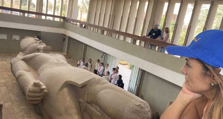 Salle intérieure abritant une statue colossale allongée de Ramsès II avec des touristes observant depuis une balcon et le niveau du sol.