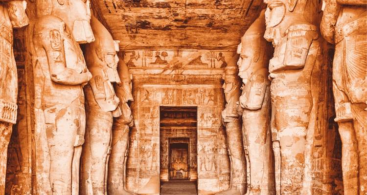 Couloir en grès symétrique bordé de statues de pharaons sculptées menant à une porte sombre à Abu Simbel.