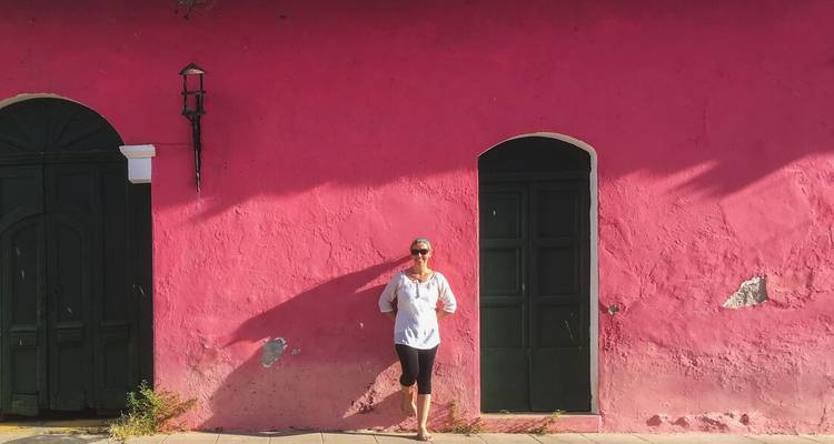 Traveller posing against a vivid pink colonial wall with arched doorways.