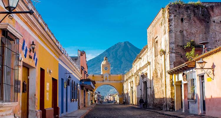Colourful colonial street in Antigua Guatemala with Santa Catalina Arch and Agua Volcano backdrop.
