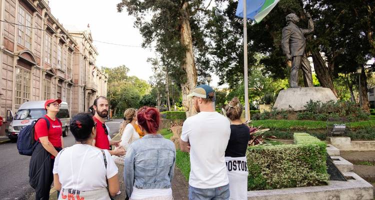 Le guide conduit un petit groupe à travers un parc urbain verdoyant situé près de bâtiments historiques.