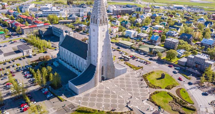 Drone view of Hallgrimskirkja church dominating Reykjavik’s colorful cityscape.