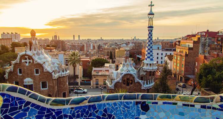 Iconisch mozaïekterras van Park Güell met uitzicht op de Barcelona skyline bij zonsopgang.