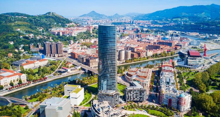 El moderno skyline de Bilbao con la Torre Iberdrola de cristal junto al río sinuoso y las colinas que la rodean.