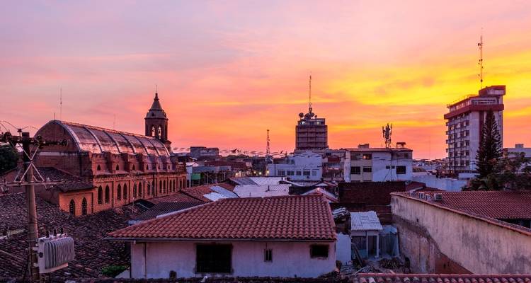 Atardecer vibrante de color naranja y rosa sobre los tejados de la ciudad y torres lejanas