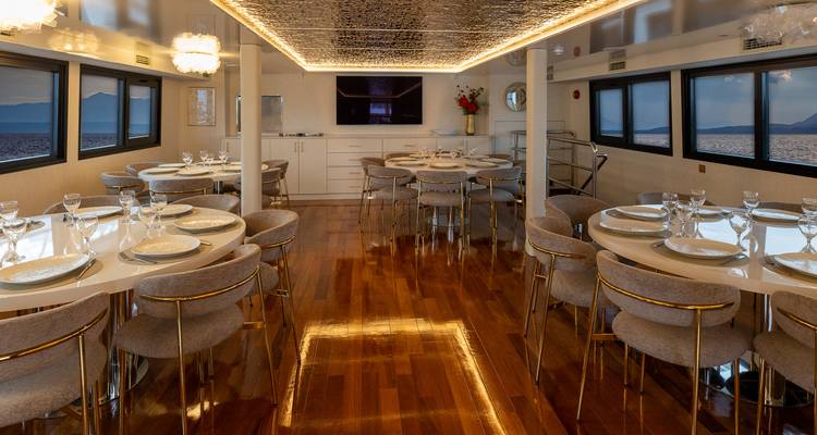 Comedor elegante con mesas redondas bien organizadas, luces del techo reflejadas y ventanas panorámicas.
