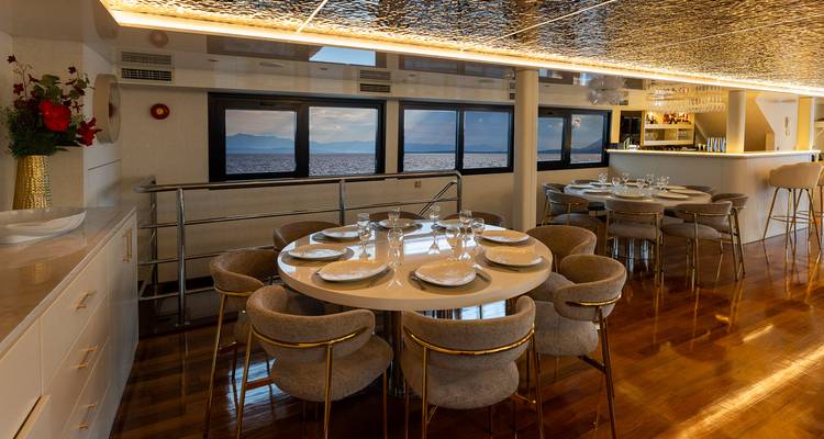 Otro ángulo del salón comedor del yate mostrando pisos pulidos, bar y vista al océano.