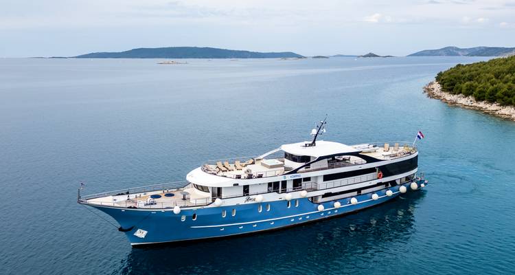 Élégant yacht bleu croisant le long de la côte croate boisée et des îles