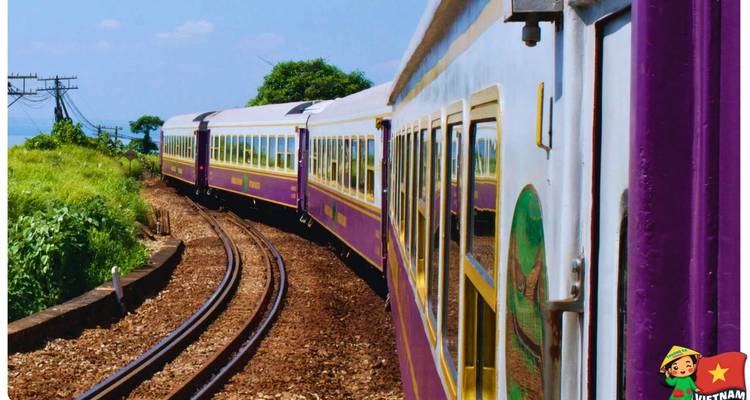 Vue latérale d'un train touristique coloré prenant un virage avec un badge dessiné de style cartoon du Vietnam.