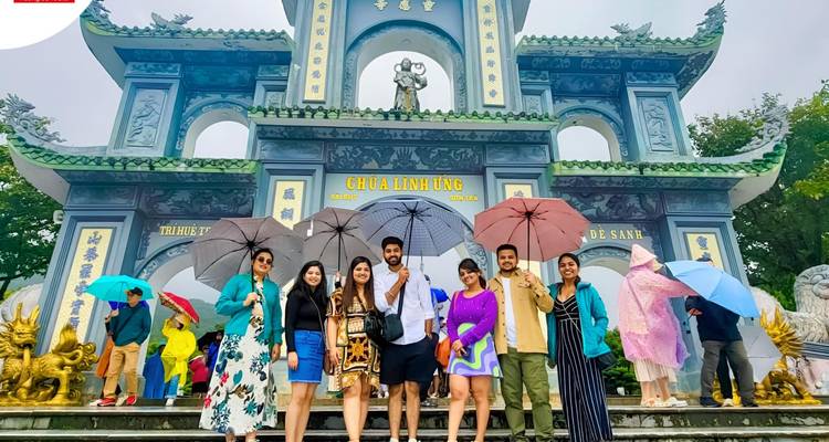 Les touristes tenant des parapluies colorés posent sur les marches du temple sous une magnifique porte bleue ornementée.