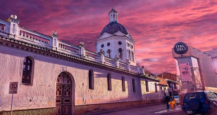 Historische Kirche mit Kuppeldach und Kolonialstraße unter einem lebhaften rosa Sonnenuntergangshimmel