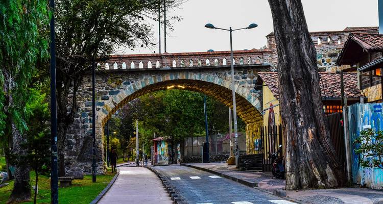 Steinbogenbrücke, die einen ruhigen Parkweg mit Bäumen in der Stadt überspannt