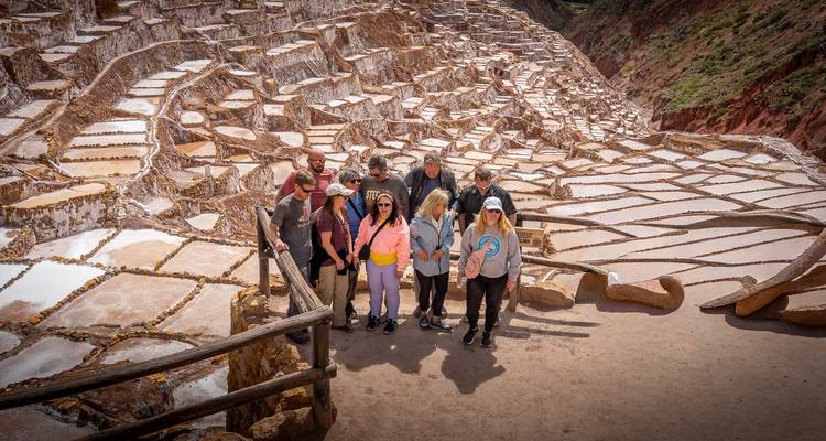 Un groupe de touristes se rassemble sur une plateforme surplombant la vaste mosaïque des bassins salants de Maras.