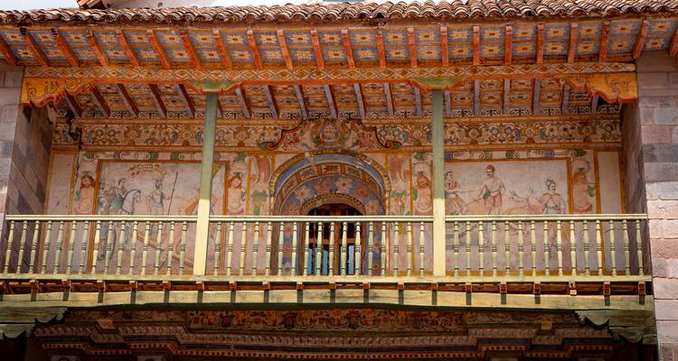Balcon richement peint et facade à fresques d'un intérieur d'église andine historique.