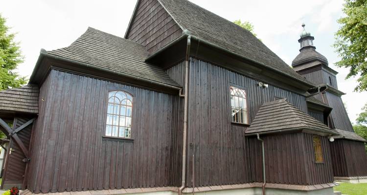 Close-up view of a dark-wooden historic church with steep shingled roofs