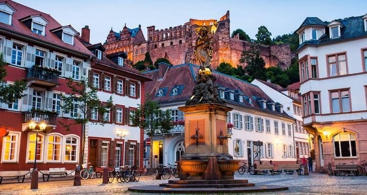Vue en fin d'après-midi de la fontaine de la Place de la Vieille Ville de Heidelberg avec les ruines du château illuminées au-dessus.