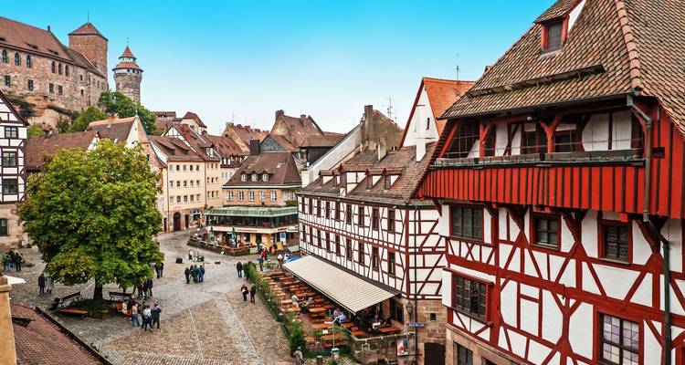 Historische Straßen der Nürnberger Altstadt mit Fachwerkhäusern und Burgmauern, die von Besuchern wimmeln.