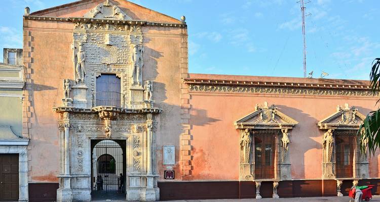 Ornate pink colonial palace façade with sculpted stone doorways in Mérida’s historic centre