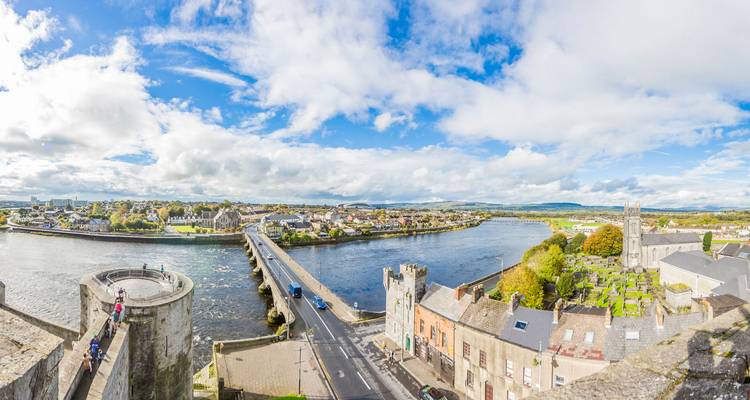 A panoramic view over Limerick shows King John’s Castle, the River Shannon, and bridges beneath dramatic clouds.