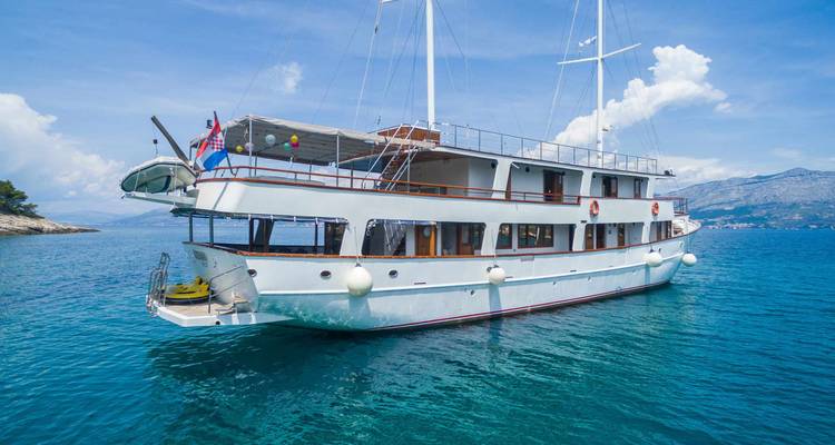 Zijkant van een modern klein cruiseschip dat drijft op kalme Adriatische wateren onder blauwe hemel.