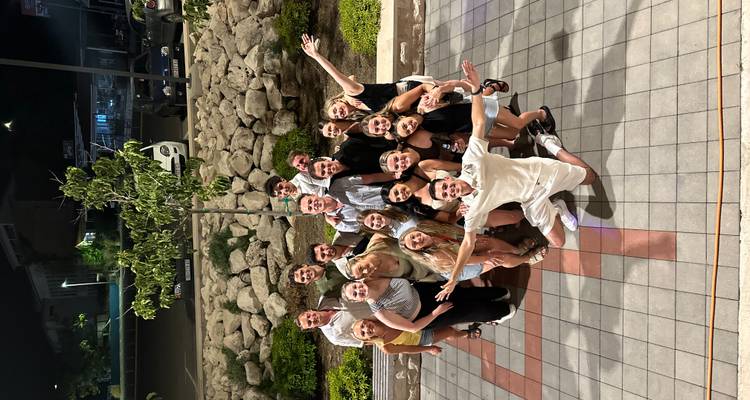 Grote groep jonge reizigers die vrolijk poseren voor een nachtfoto op een binnenplein met tegels