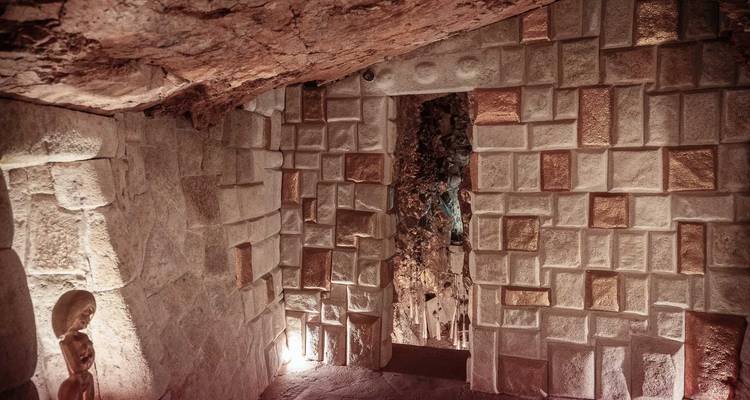 Cámara de piedra con patrones de bloques intrincados que conducen a otra sala iluminada.