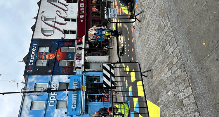 Arbeiders schilderen kleurrijke geometrische patronen op winkelfronten in Camden, inclusief een 'I ❤️ LONDON' muurschildering.