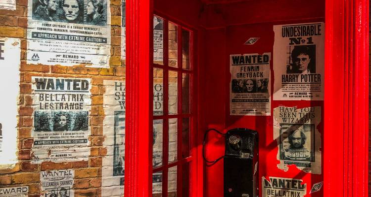 Cabine téléphonique de style britannique rouge vif décorée avec des affiches de recherche Harry Potter.