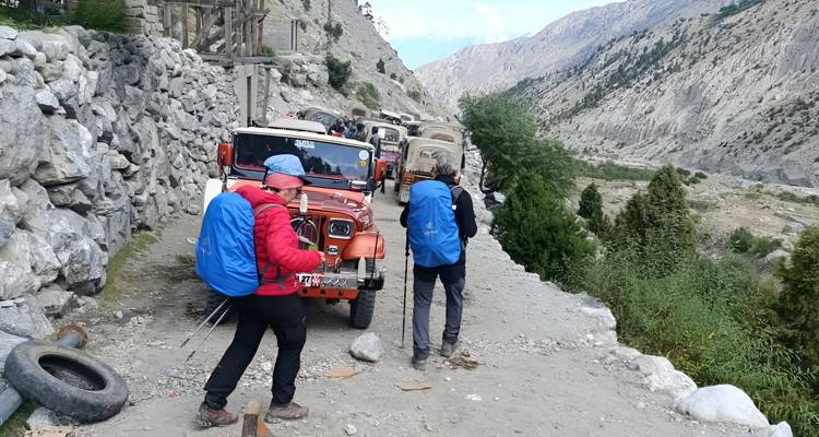 Les véhicules tout-terrain et les randonneurs se tiennent sur un sentier rocheux de montagne creusé dans la paroi escarpée d'une vallée.