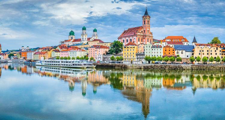 Colorful riverside skyline of Passau with its baroque cathedral reflected in the calm Danube waters.