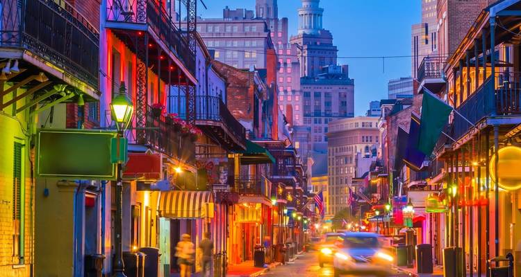 Vibrant Bourbon Street in New Orleans glowing with multicolored lights and lively evening crowds.