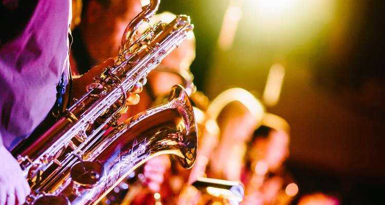 Close-up of saxophonists performing under warm stage lights, capturing the energy of live jazz.